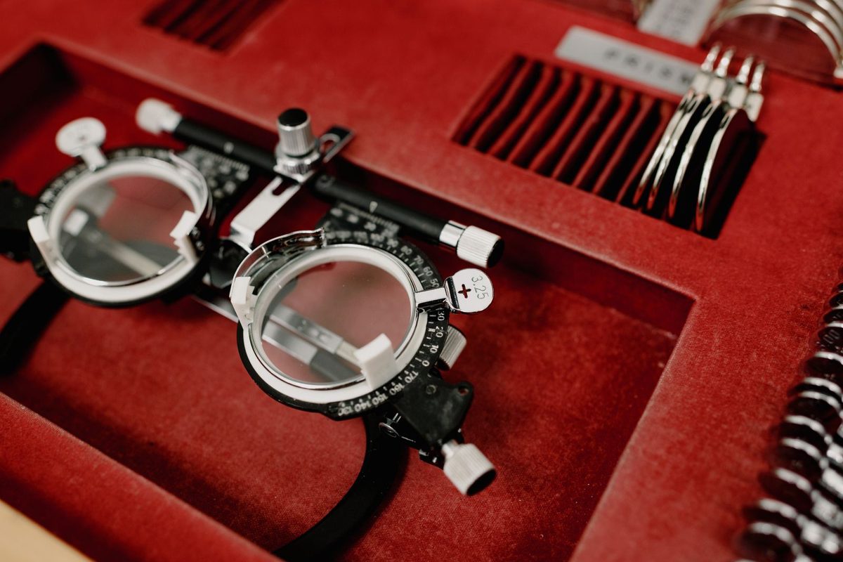 An optician's trial frame with a +3.25 lens clipped into it, on a red felt tray